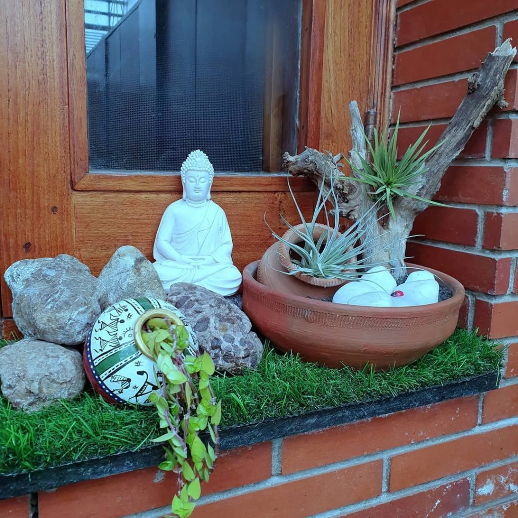 Buddha statue with stones and plants in a garden nook