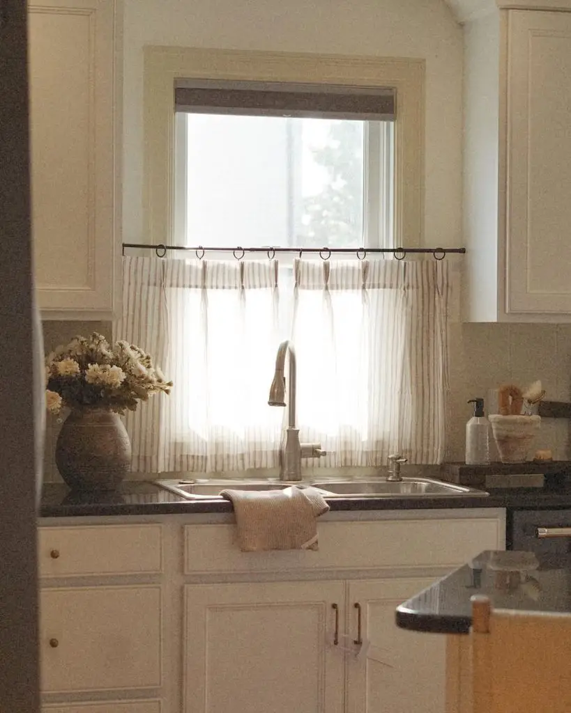 Serene kitchen with farmhouse sink, modern faucet, and flower vase.