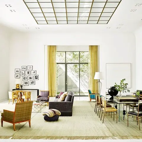 Bright, open-concept living space with skylights, yellow curtains, grey sofa, and midcentury modern furniture.