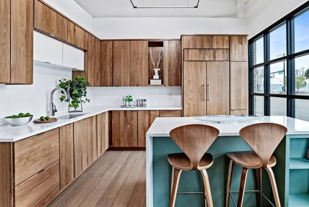 Modern kitchen with natural wood cabinets, white countertops, and a green island base