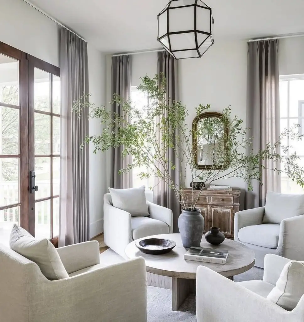 Bright living room with gray curtains, white armchairs, and natural decor