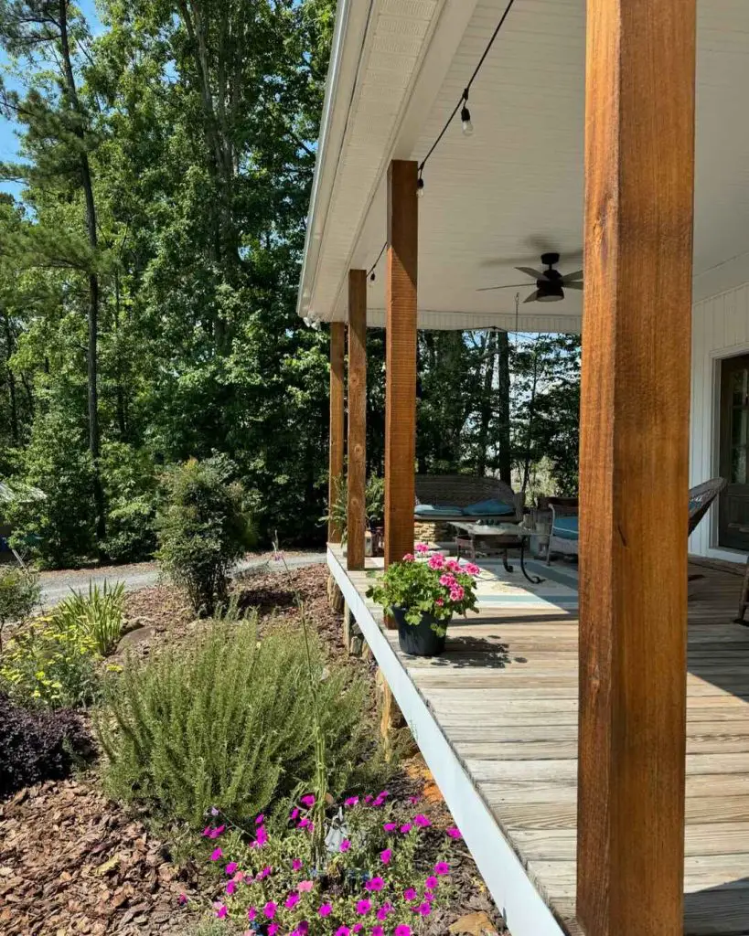 Inviting porch with wooden posts, pink flowering plants, and surrounding greenery