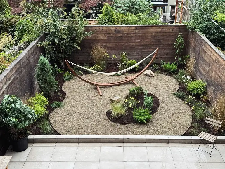 Outdoor oasis with a hammock, gravel path, and surrounding greenery.
