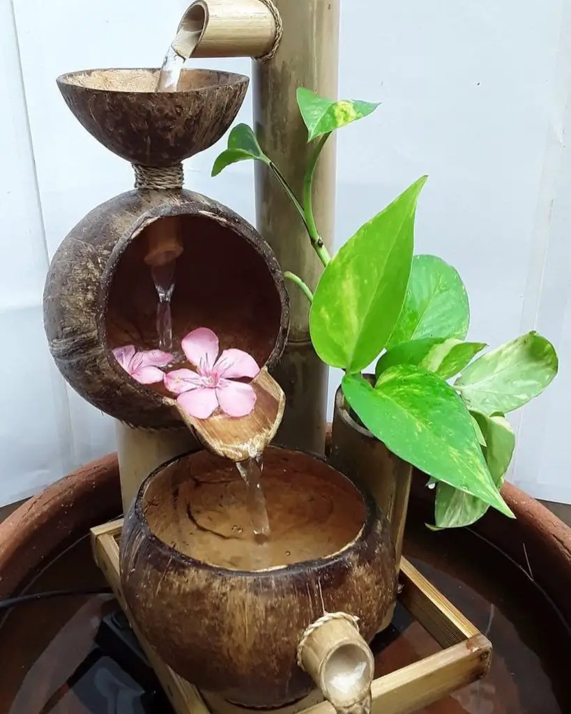 Water fountain with bamboo spout, coconut bowls, and pink flowers