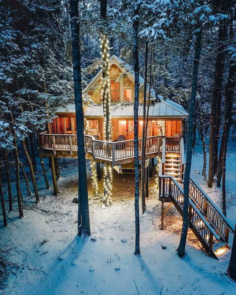 Charming treehouse cabin illuminated in snow.