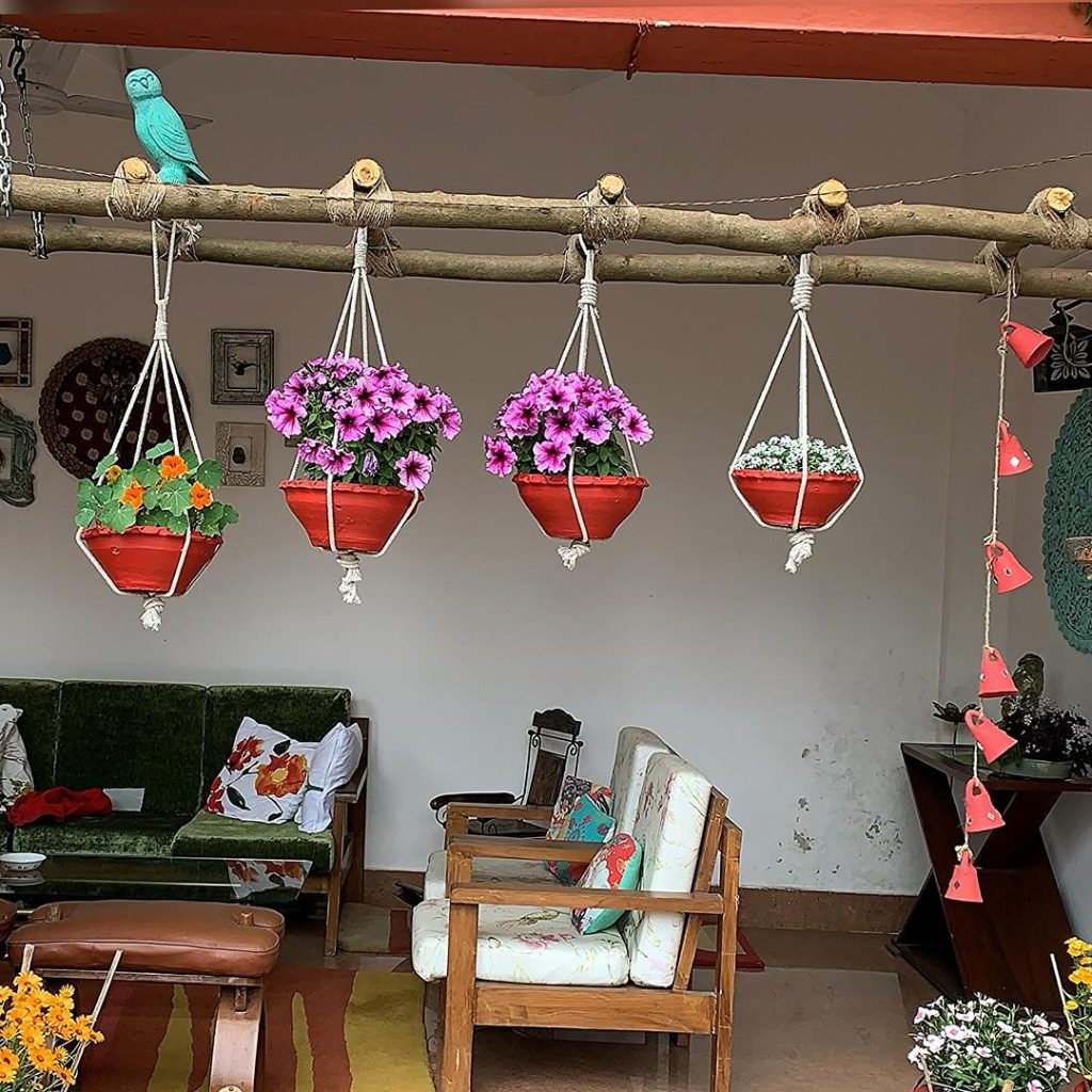 Outdoor seating area with hanging flower planters and a cozy sofa.