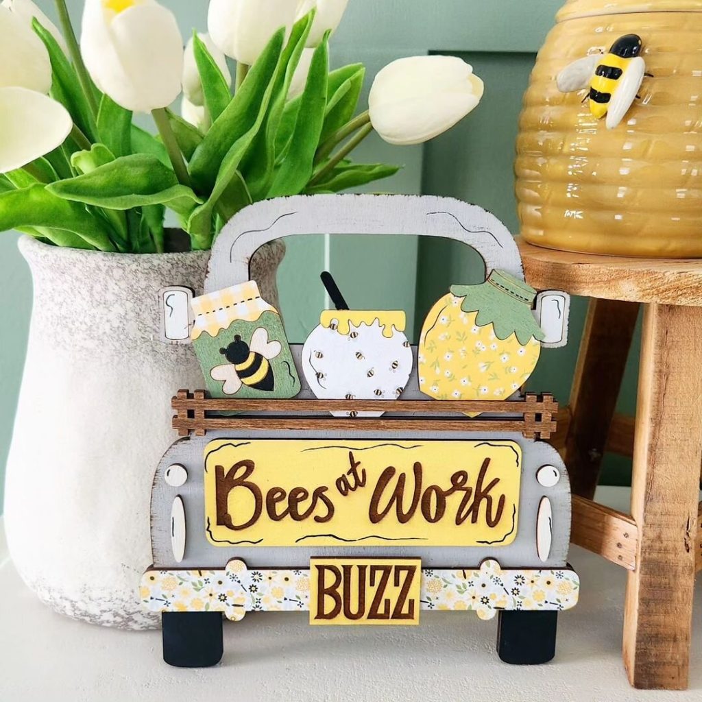 Wooden truck decor with honey jars and the phrase 'Bees at Work' alongside a vase of tulips and a honey jar