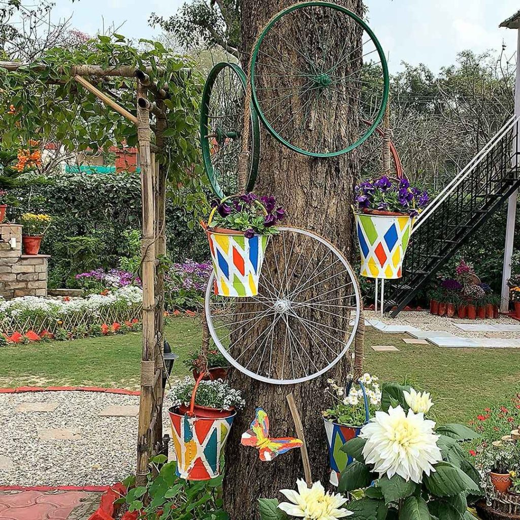 Bicycle wheels and colorful pots on a tree, decorated with flowers and a butterfly