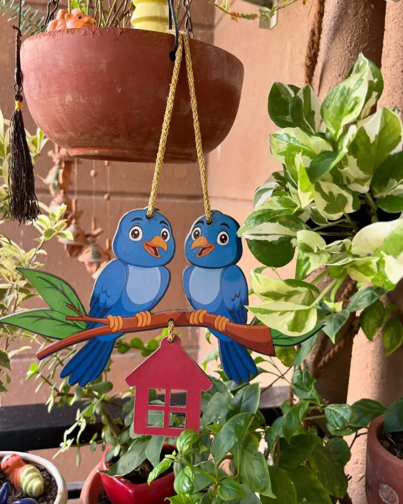 Hanging decoration of blue birds and a red birdhouse in a garden.
