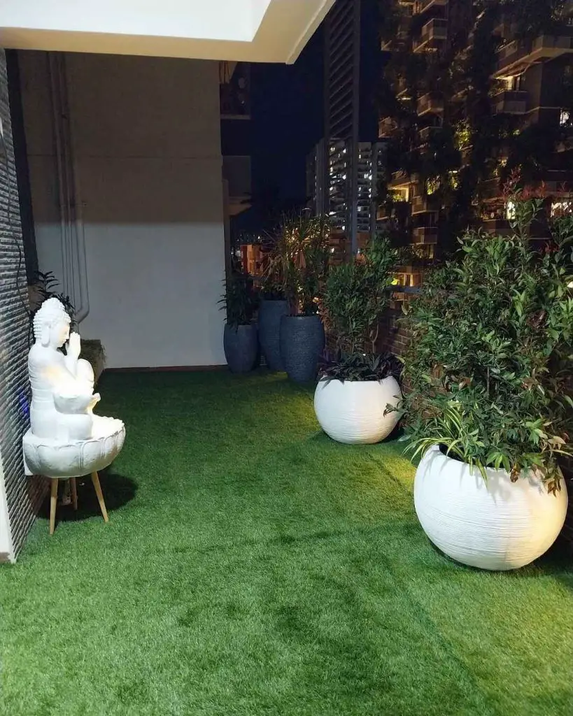 Balcony garden featuring Buddha statue white sphere planters and artificial turf illuminated at night