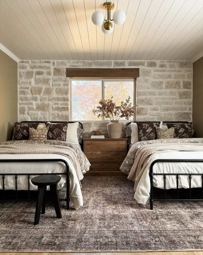 Twin bedroom with stone walls iron beds and warm lighting
