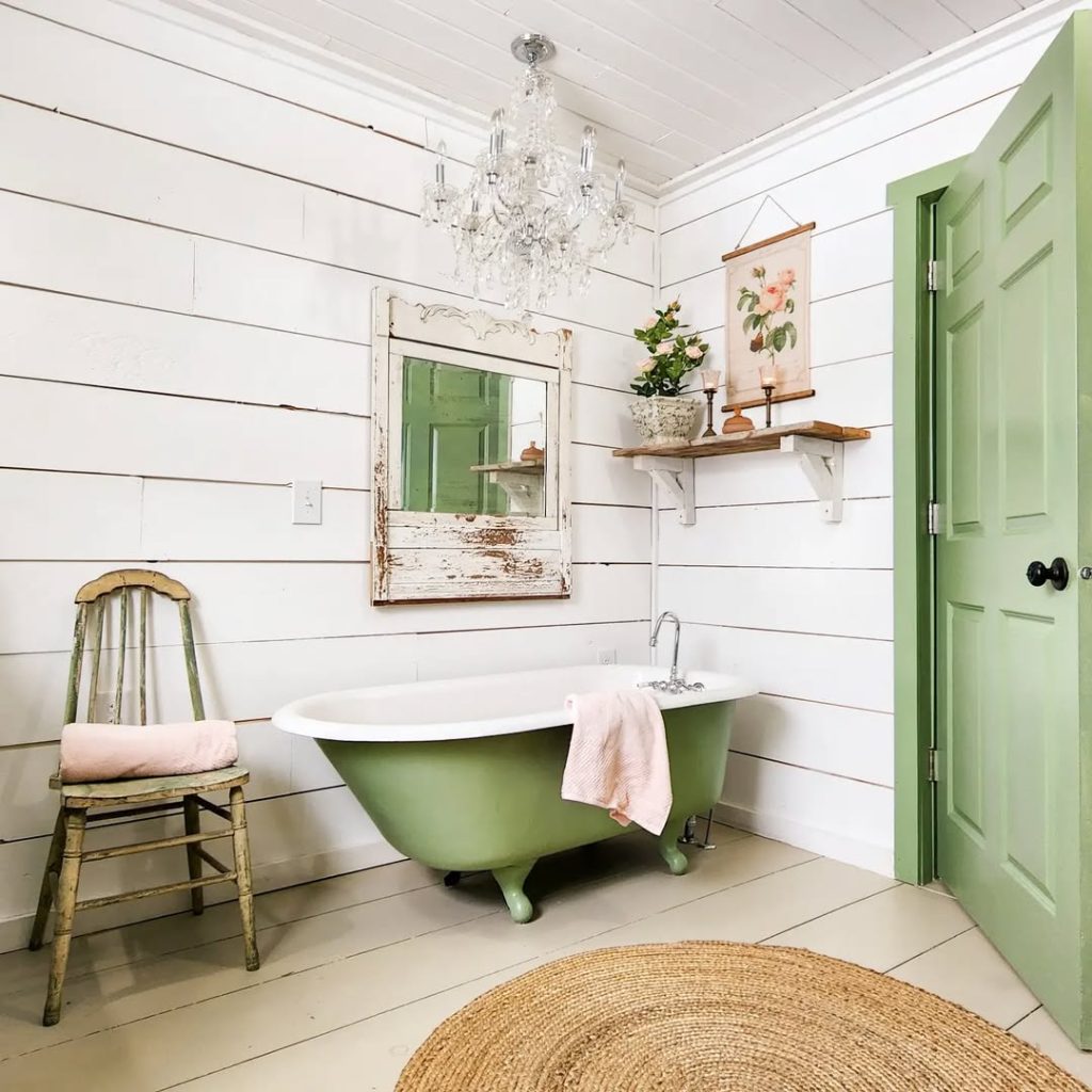 Vintage bathroom featuring green tub white walls and crystal lighting
