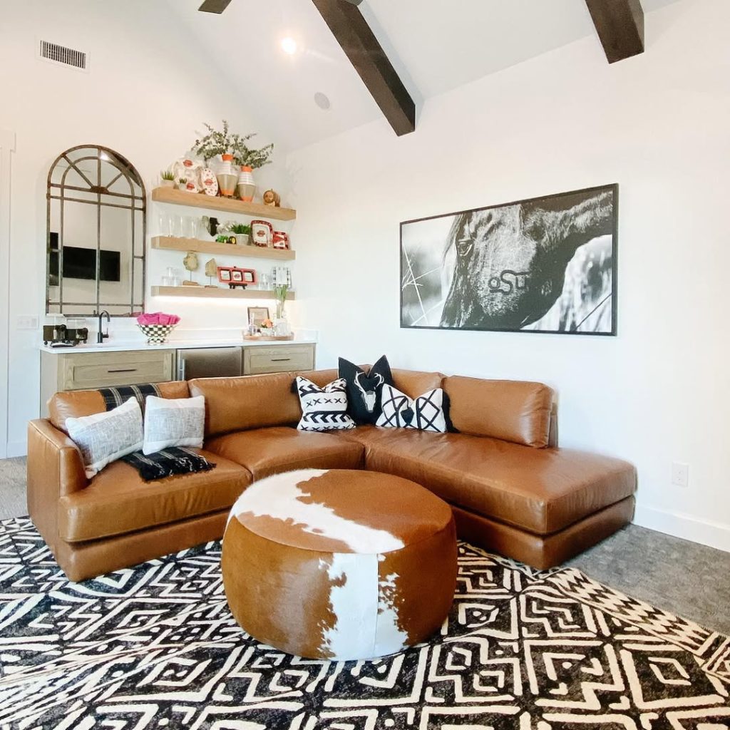 Modern farmhouse living room with exposed beams stone fireplace and vintage art