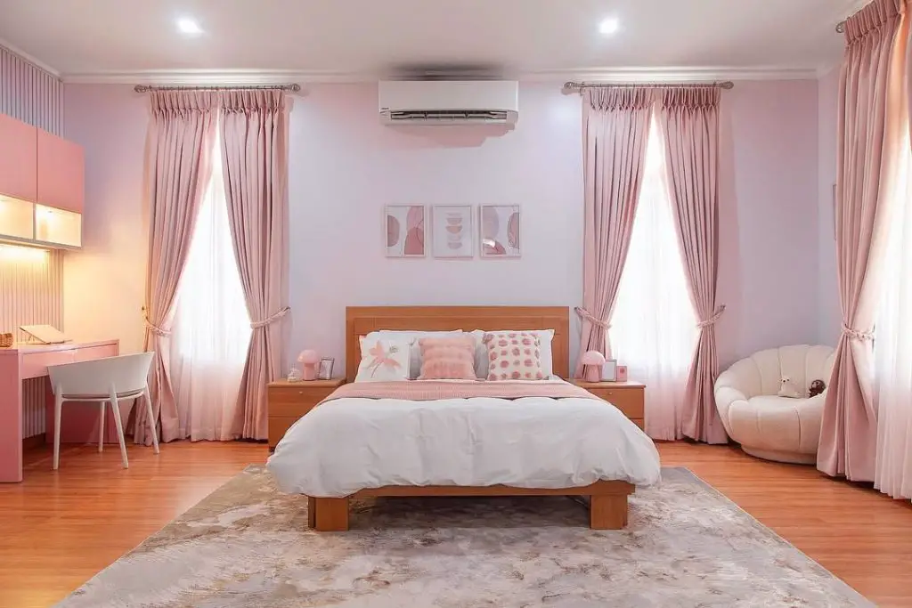Pink studio bedroom with wooden bed and shell accent chair
