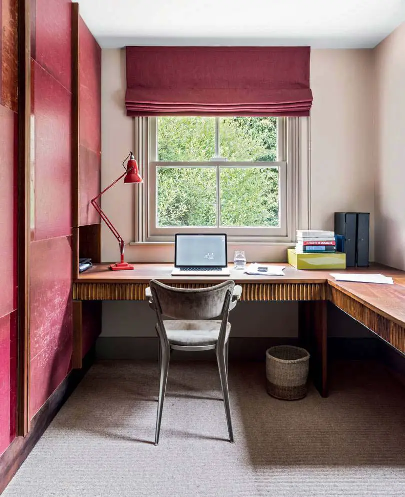 Modern minimalist office with glass partition dark walls and coral armchair