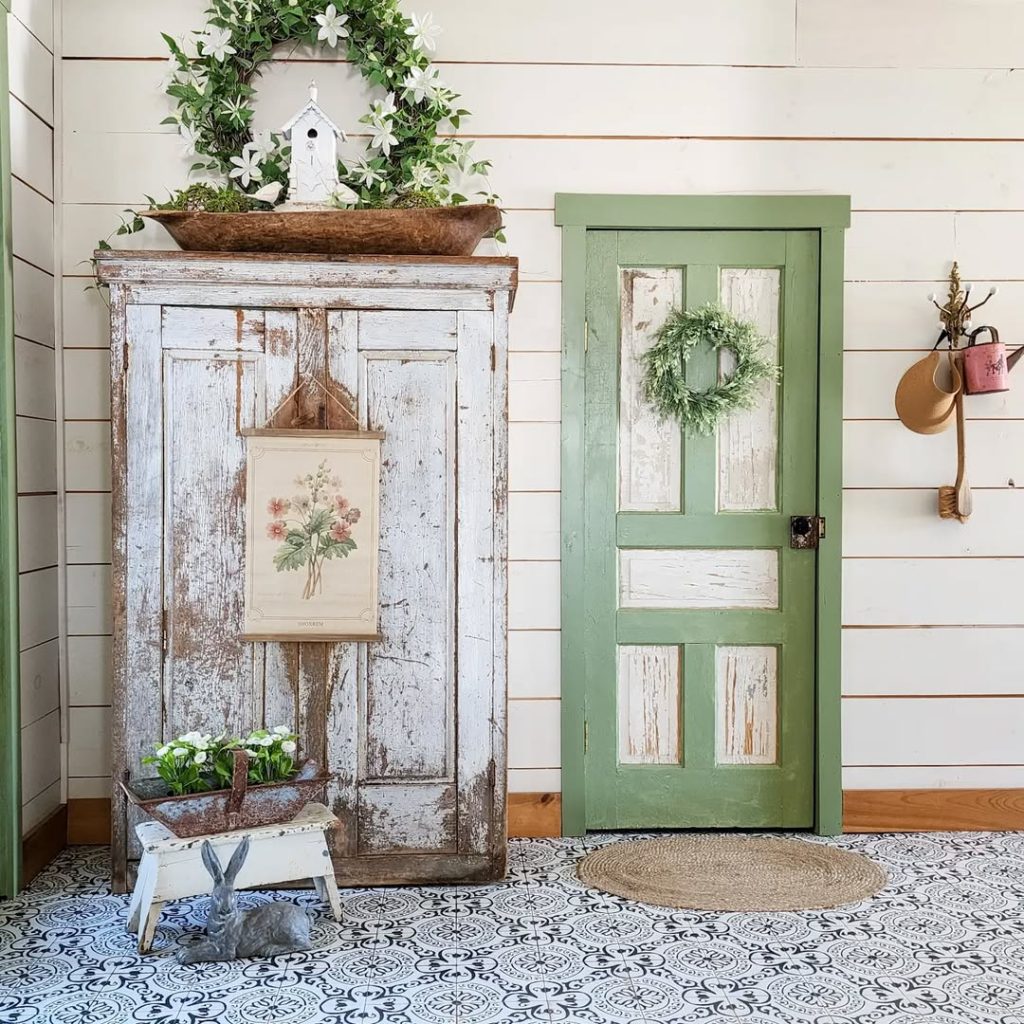 White cabinet with floral artwork and mint green door on patterned floor