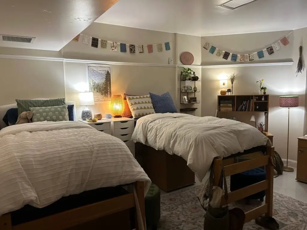 Twin dorm room with matching wooden beds warm lighting and mountain artwork
