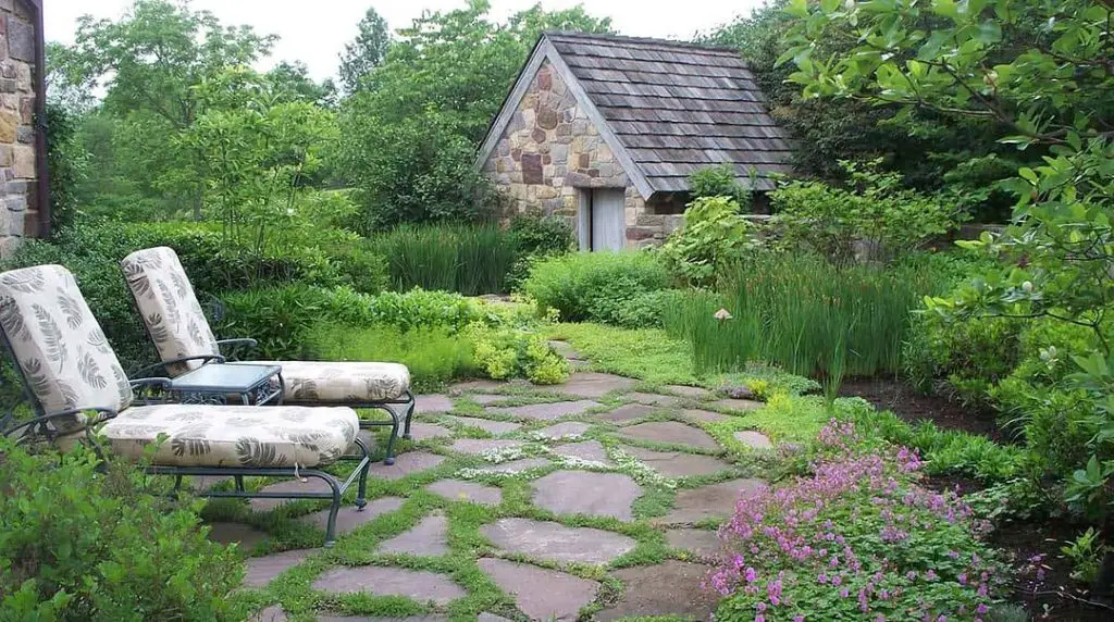 Flagstone path leading to stone cottage with cushioned patio furniture