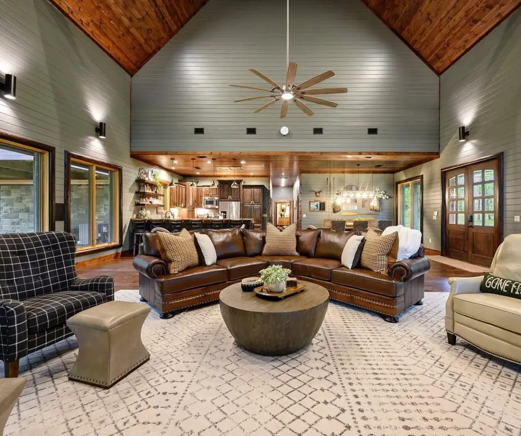 Open concept living room with vaulted ceiling leather sectional and rustic accents