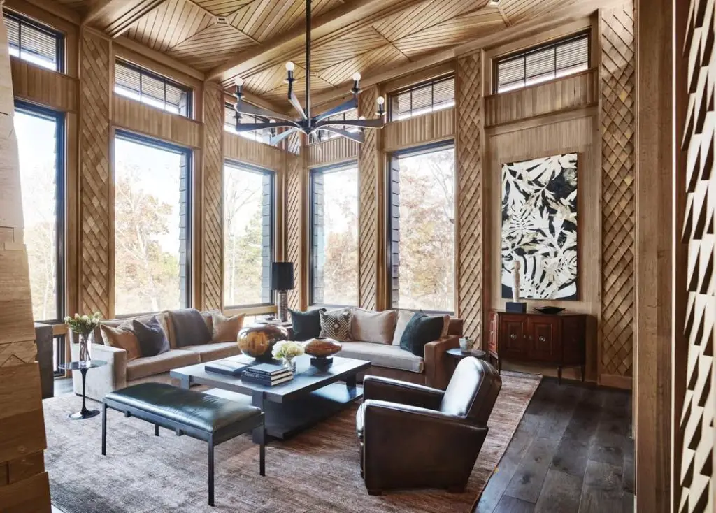 Living room with wooden walls and modern furniture overlooking forest