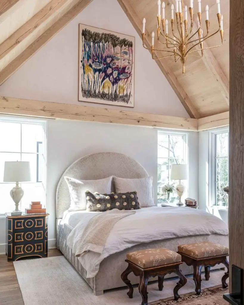 Bedroom with vaulted ceiling gold chandelier and upholstered headboard