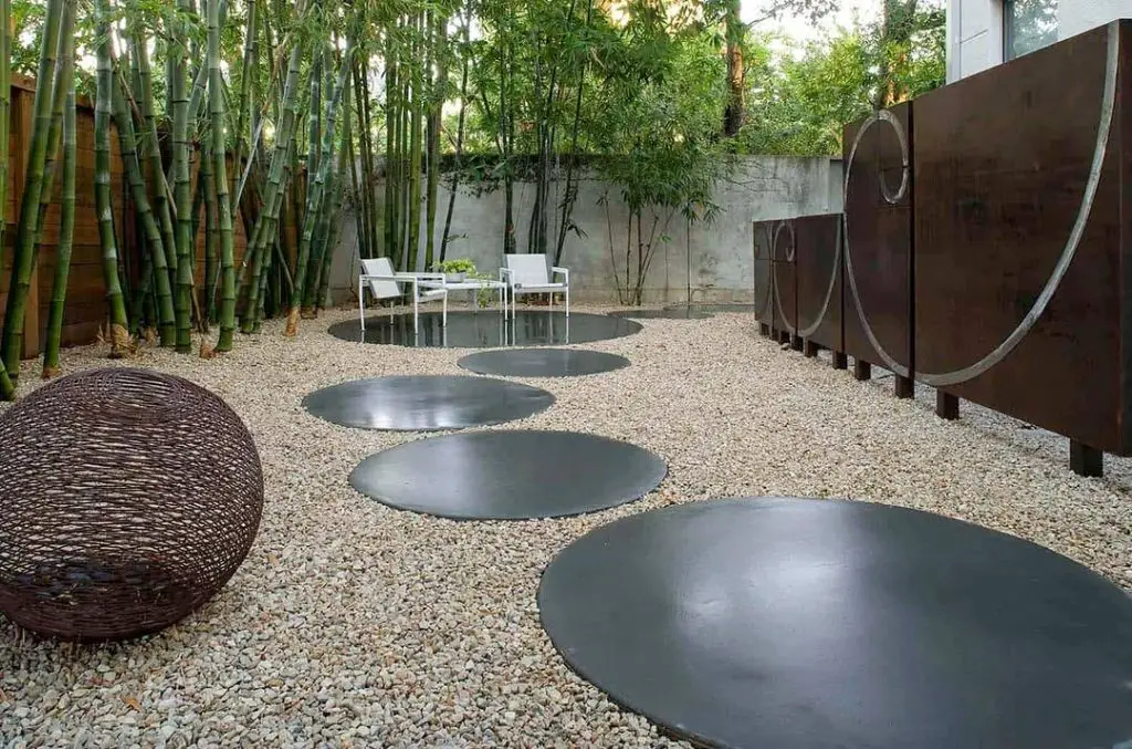 Modern circular metal stepping stones in bamboo garden with seating