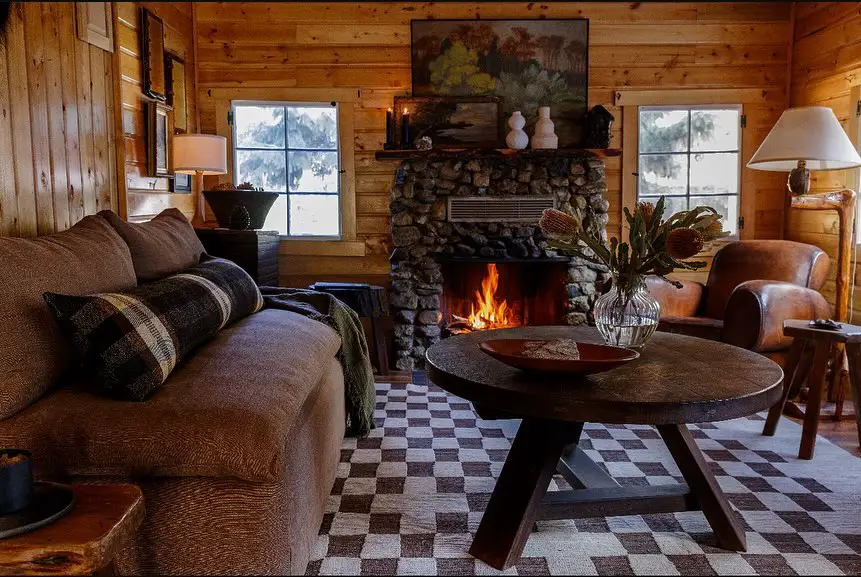 Cozy cabin living room with stone fireplace brown leather sofa and checkered rug