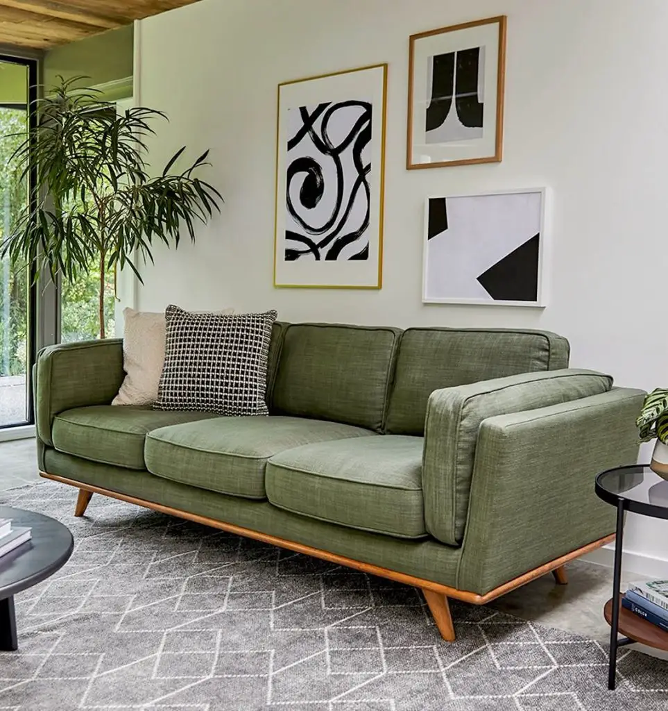 Dark green room with velvet sofa forest artwork and brass accents