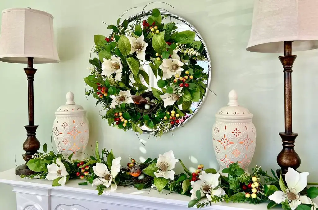 White mantel with magnolia wreath and glowing ceramic lanterns