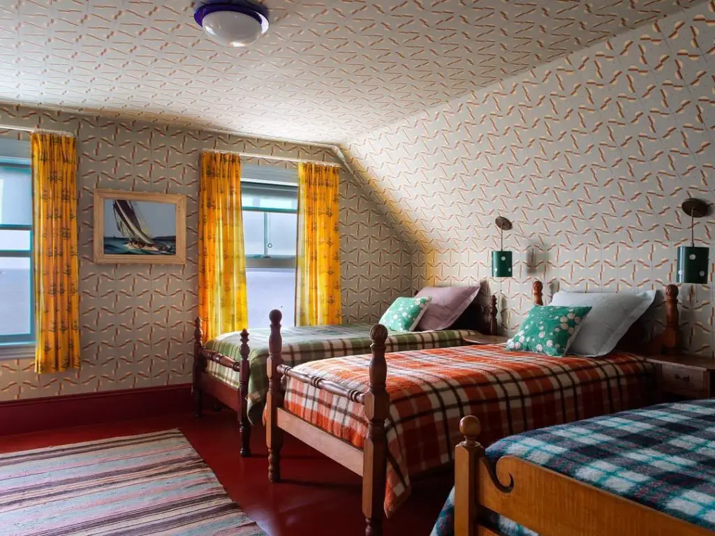Attic bedroom with yellow curtains plaid blankets and sailing art