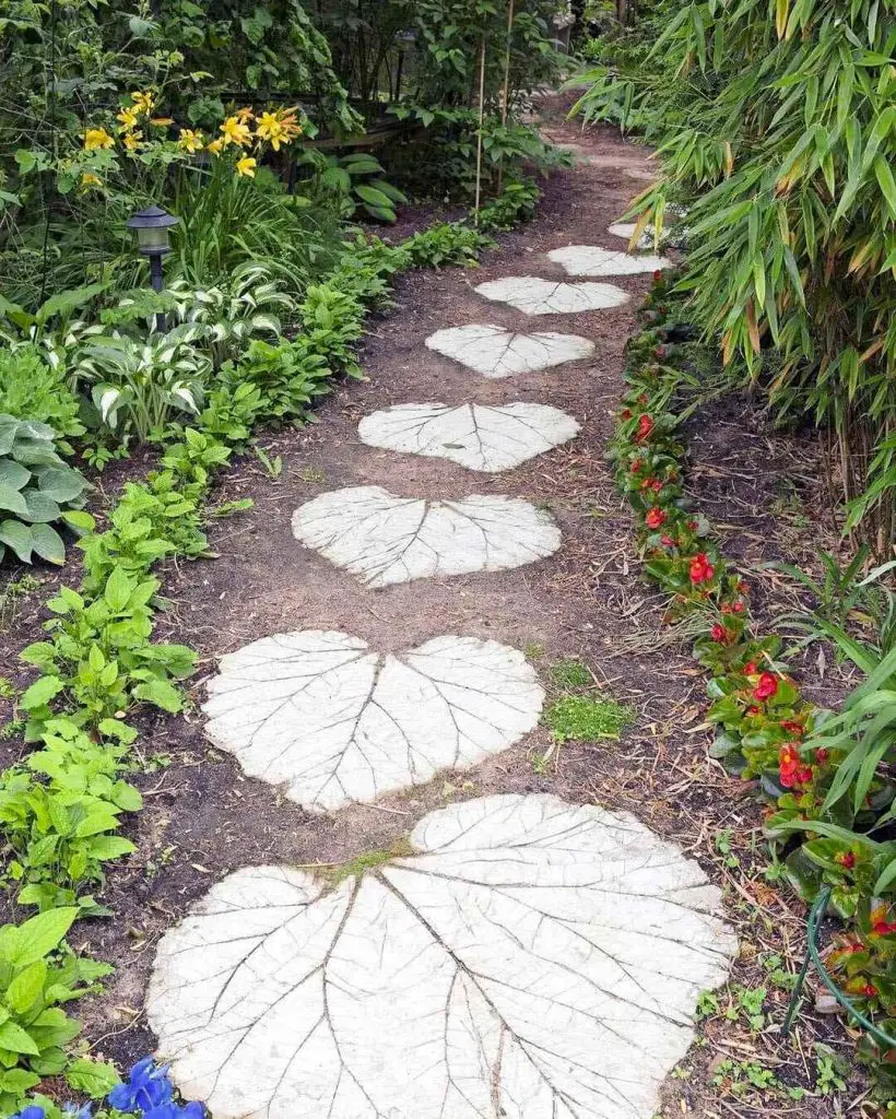 Concrete stepping stones with leaf impressions amid flowering garden