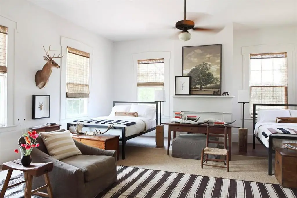 Twin bedroom with deer mount metal beds and striped rugs