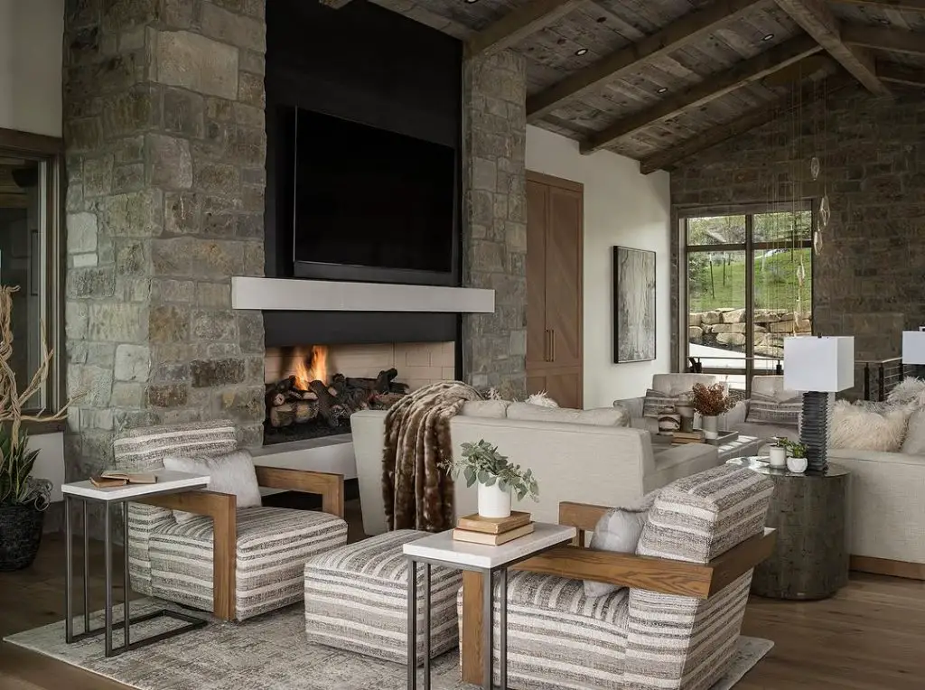 Modern mountain living room with stone fireplace striped chairs and wooden beams