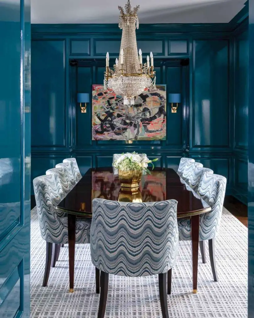 Teal dining room with crystal chandelier and wave patterned chairs