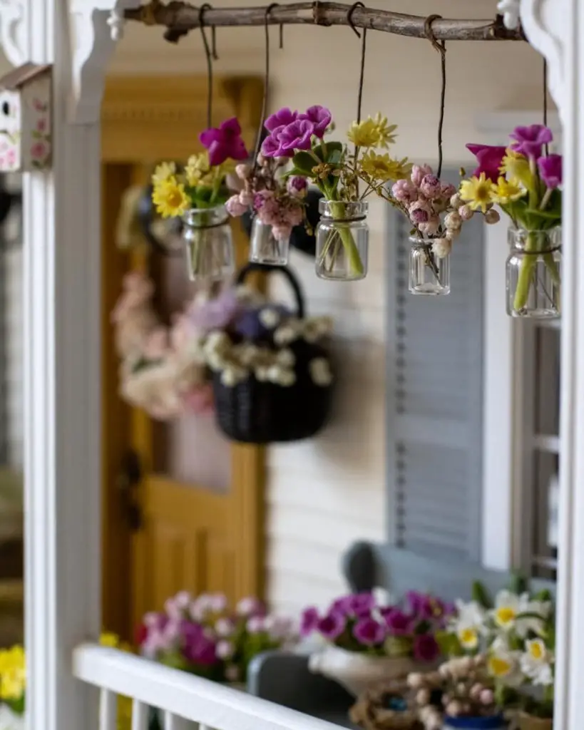 Branch with hanging glass vases filled with spring flowers