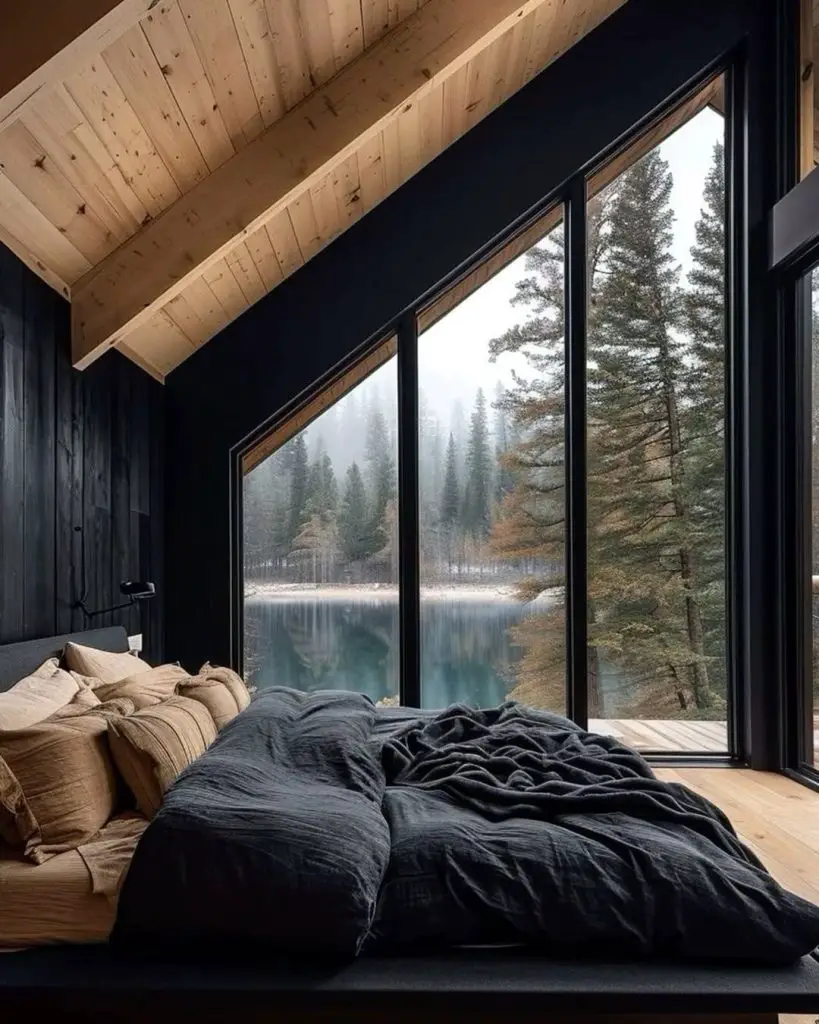 Bedroom with large windows overlooking misty lake and forest.