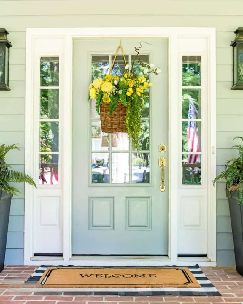 White framed door with floral basket and striped welcome mat