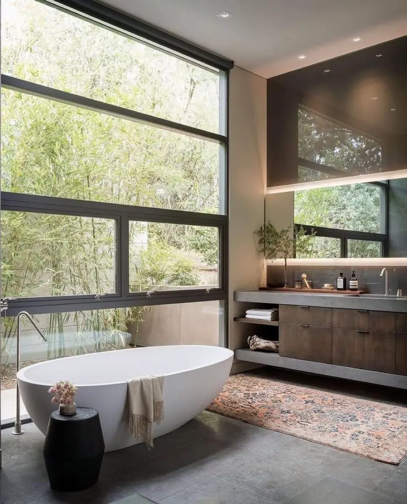 Modern bathroom with oval tub and floor to ceiling windows facing bamboo garden