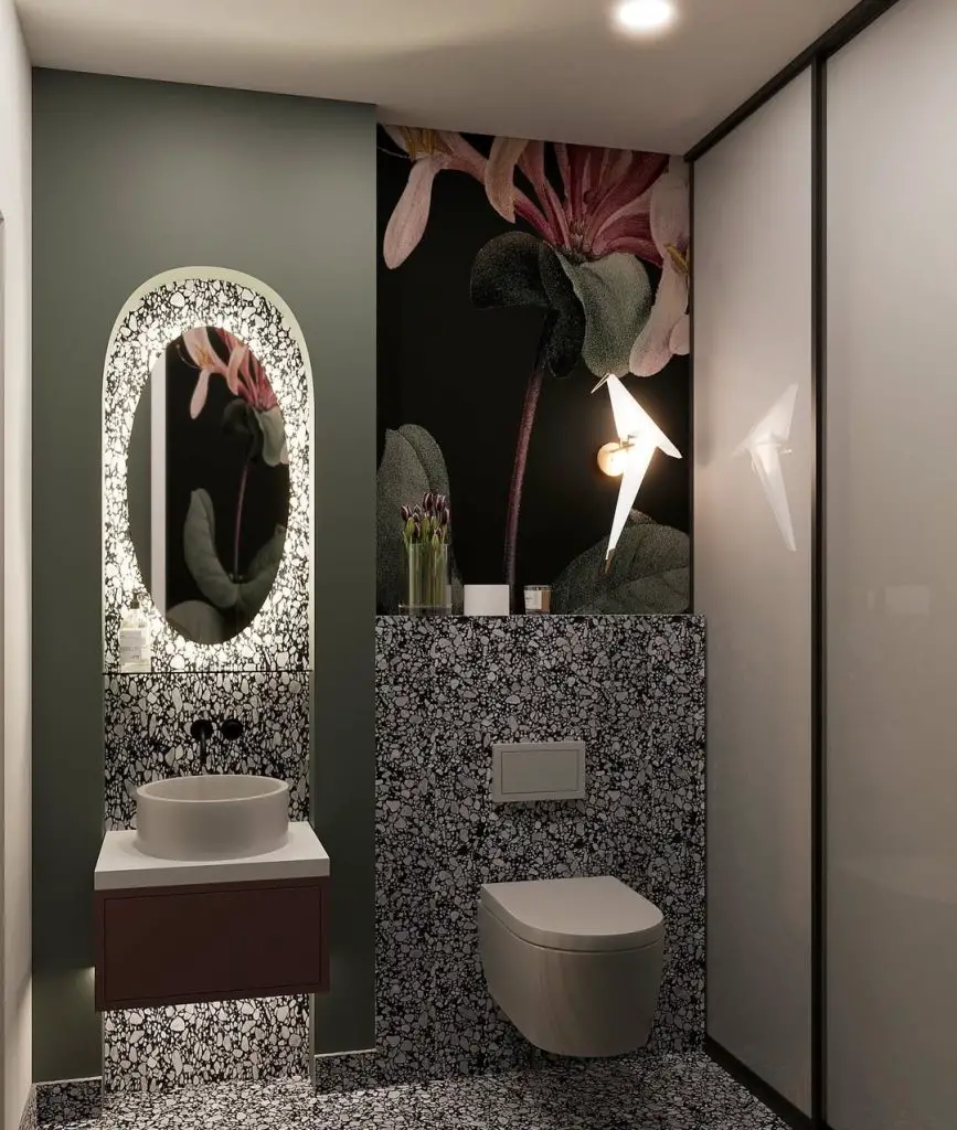 Dark bathroom with floral wall and illuminated oval mirror