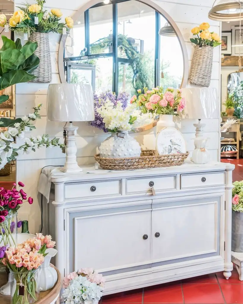 White sideboard with mirror table lamps and spring flower arrangements