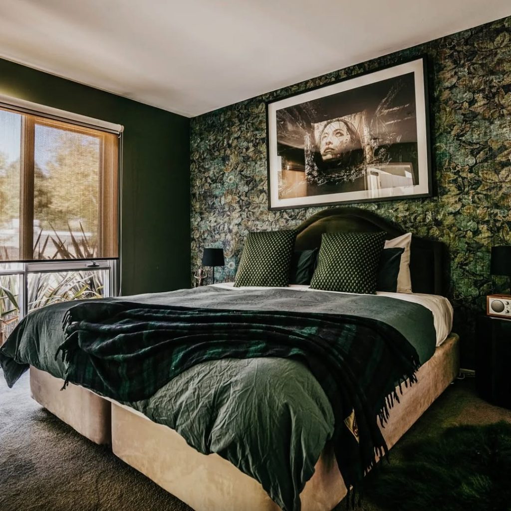 Dark green bedroom with vintage portrait and patterned wallpaper
