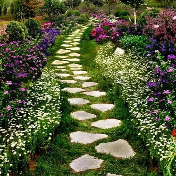Curved stone pathway winding through purple and white flowering garden beds