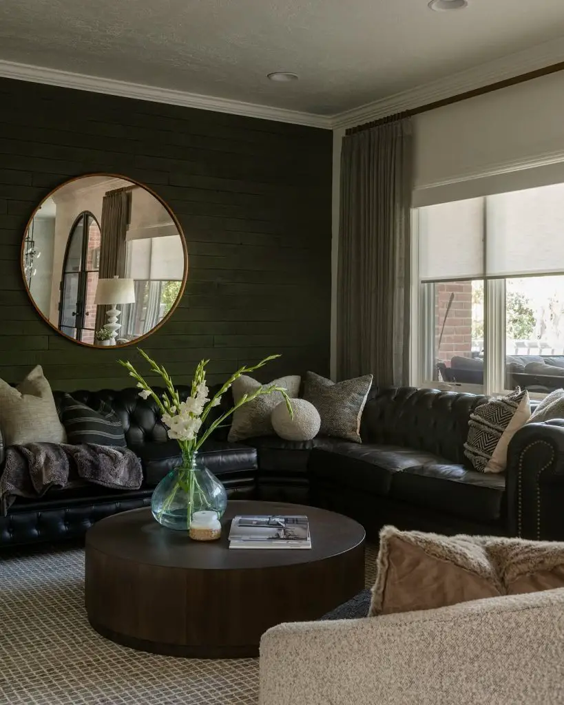 Dark green living room with leather sofa round mirror white flowers
