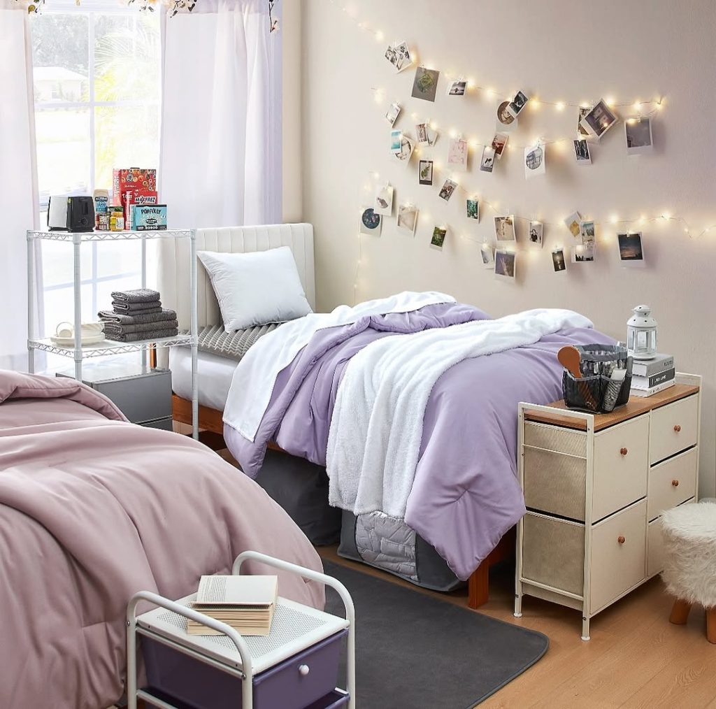 Lavender comforter with string light photo display and white shelving unit