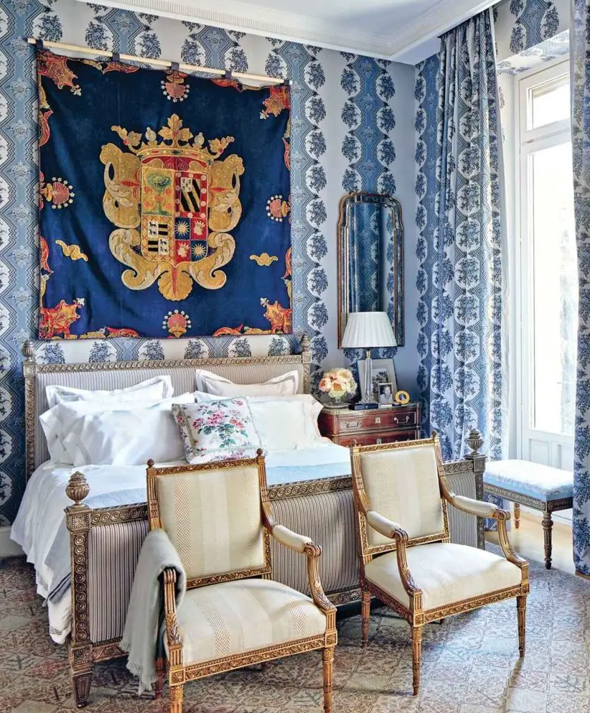 Blue bedroom with gold heraldic tapestry and ornate furniture pieces
