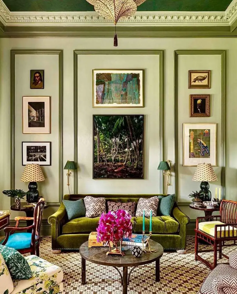 Green velvet sofa beneath ornate ceiling with vintage artwork display
