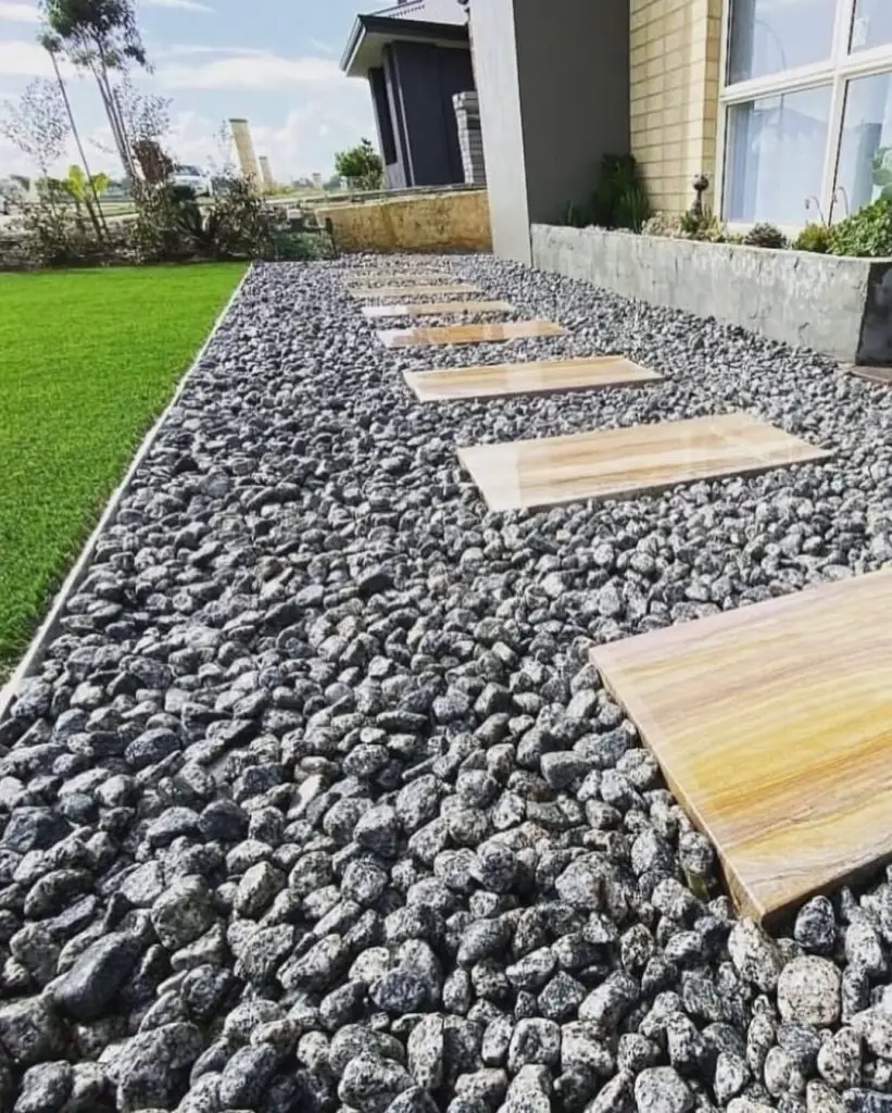 Wooden platforms set in dark gray river rock garden bed