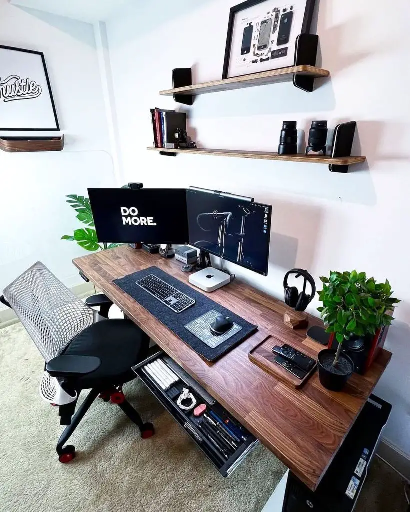 Wooden desk setup with dual monitors and floating shelves for camera gear