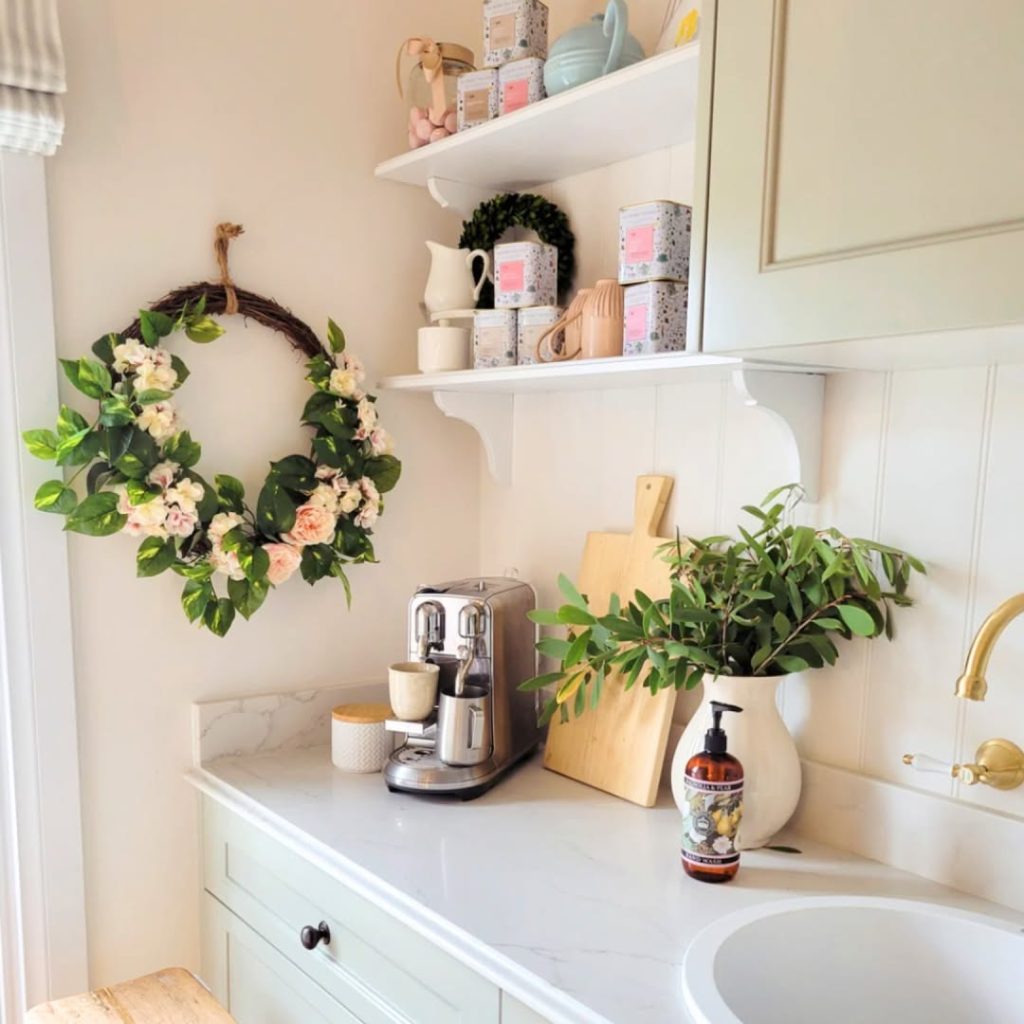 White coffee station with marble counter floral wreath and organized shelving