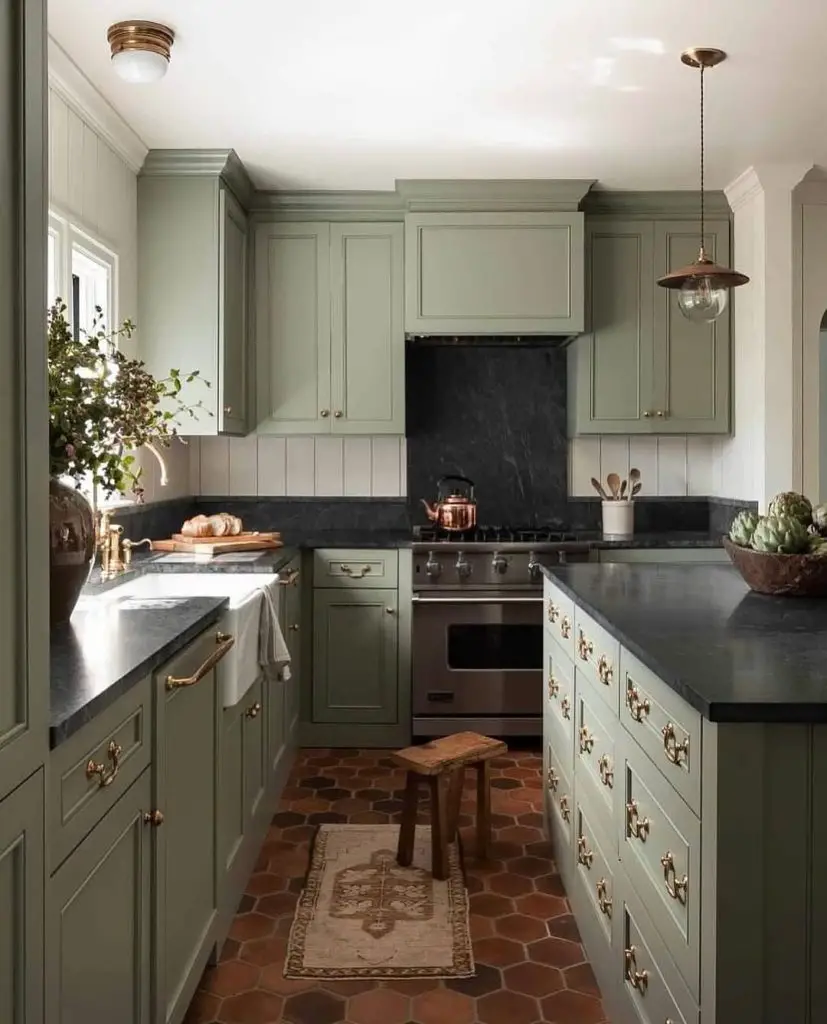 Sage green kitchen with copper accents black marble and terracotta floors